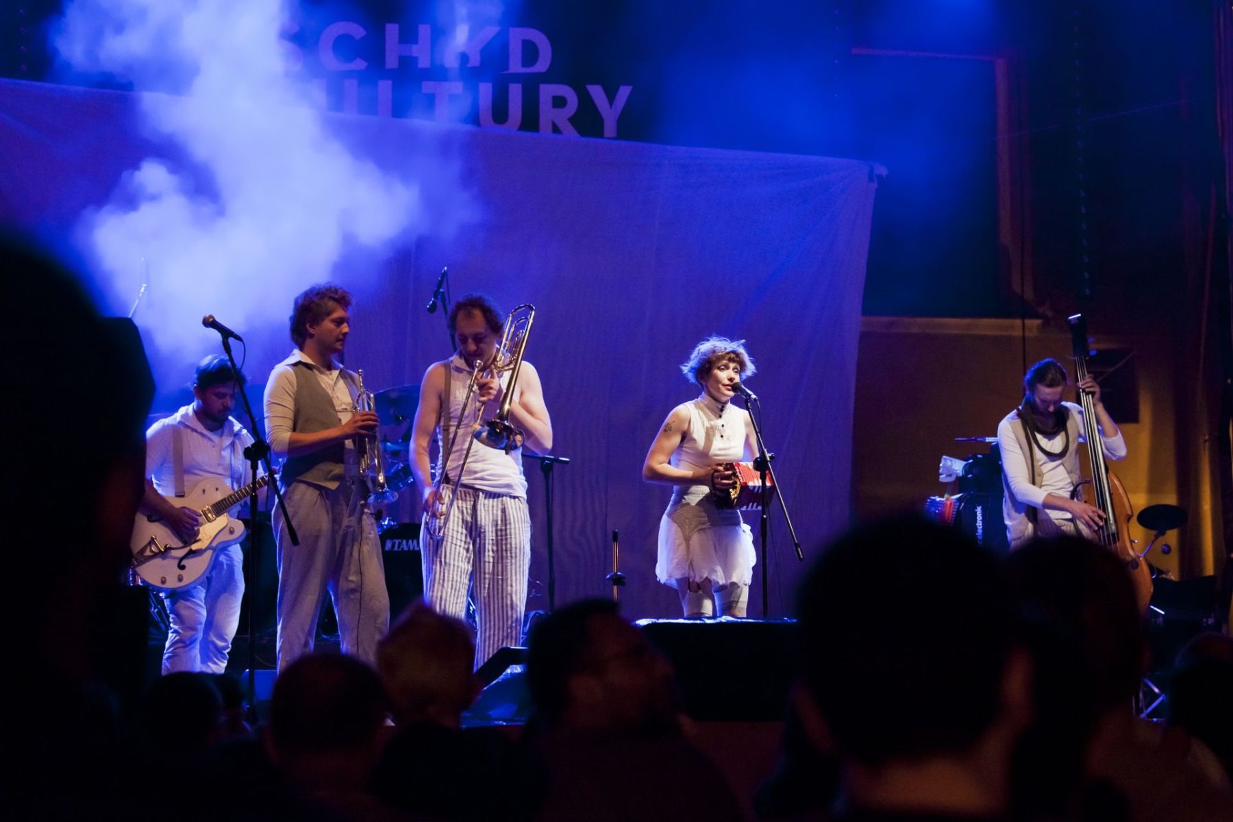 Czterech mężczyzn i jedna kobieta występują na scenie.