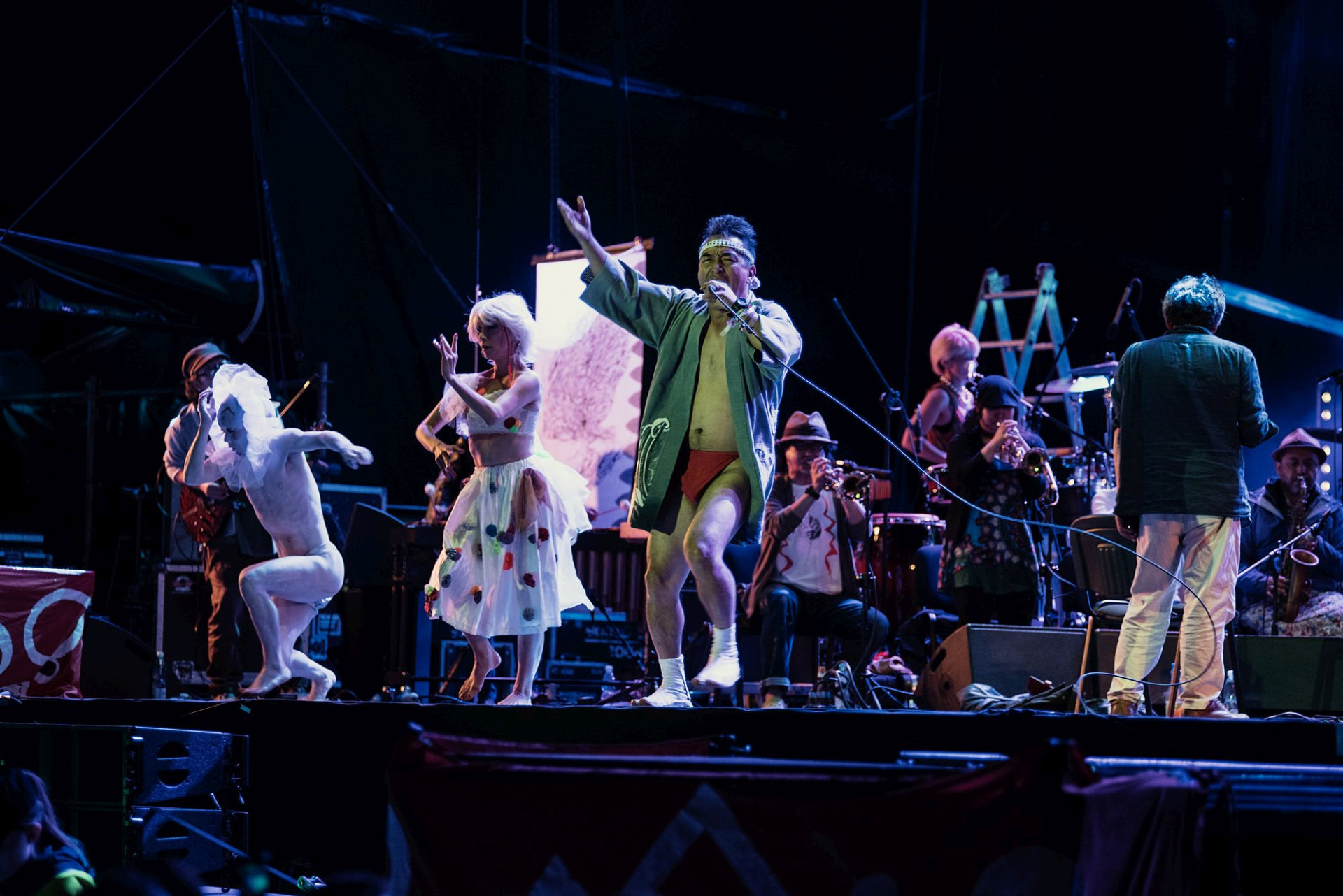 Na scenie są artyści w przebraniach. Część z nich ma na sobie tylko bieliznę.