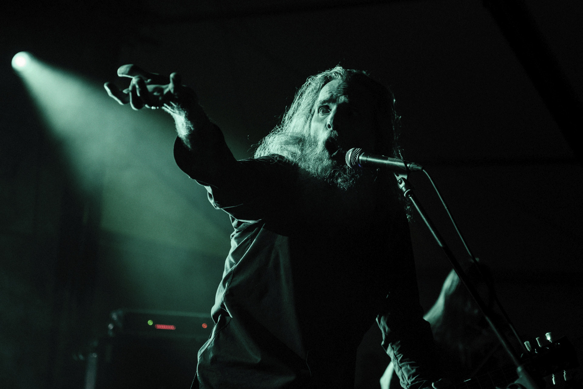 Zbliżenie na wokalistę. To starszy mężczyzna z długimi włosami.