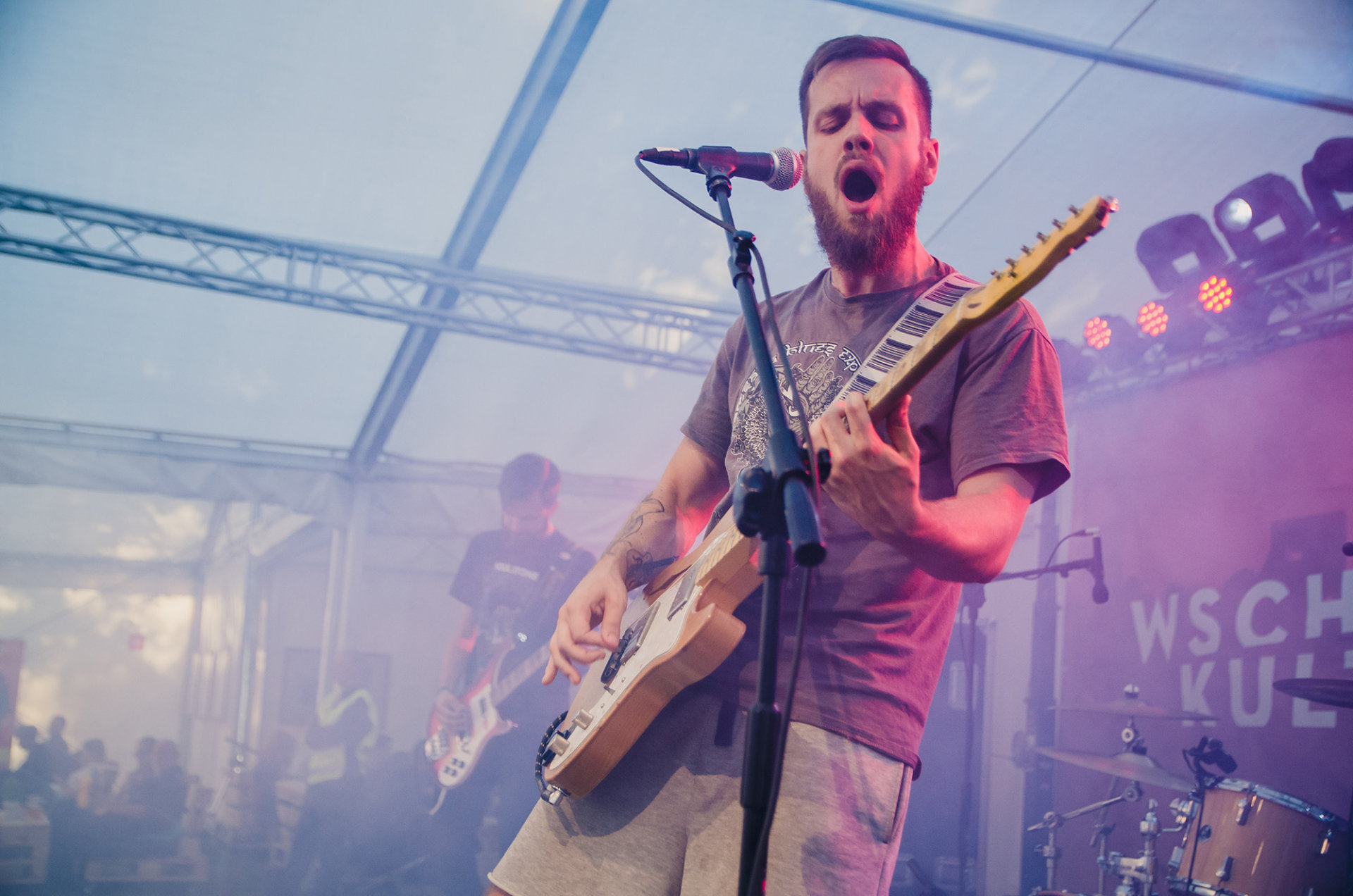 Wokalista śpiewa i gra na gitarze.