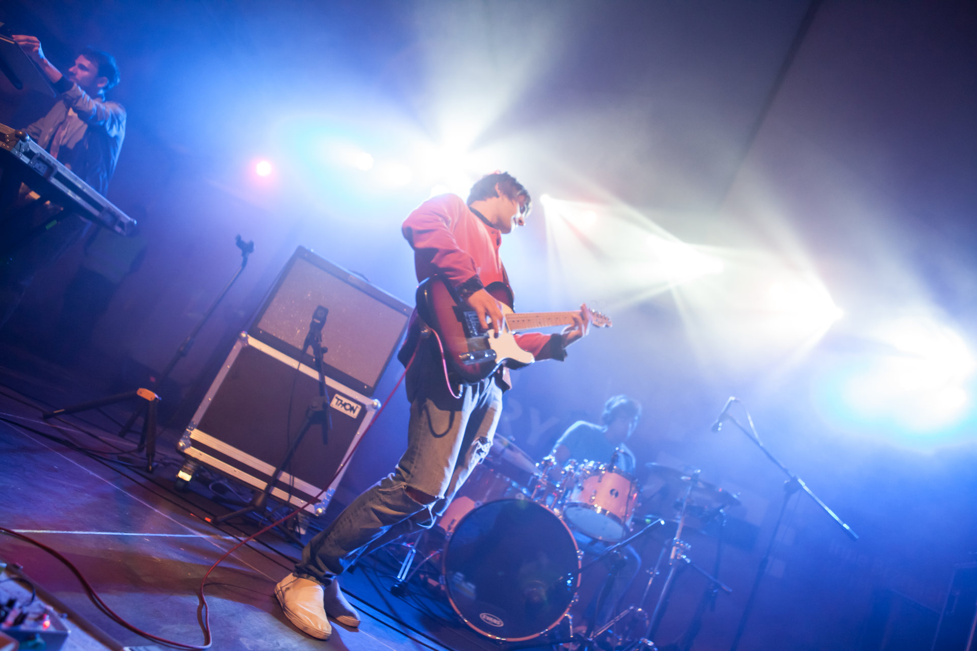 Zbliżenie na gitarzystę. W tle jest perkusista.