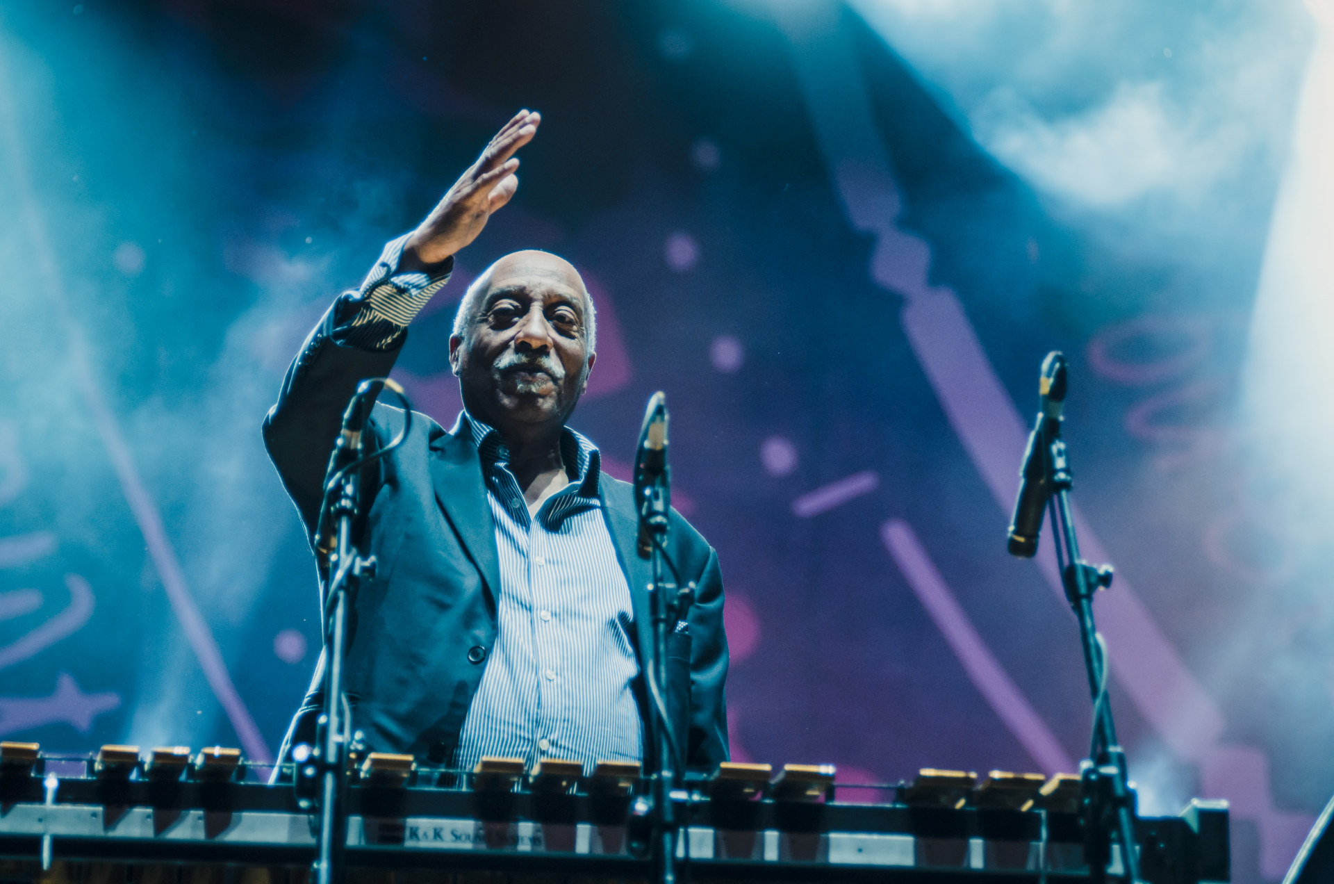 Artysta macha ręką w stronę publiczności.